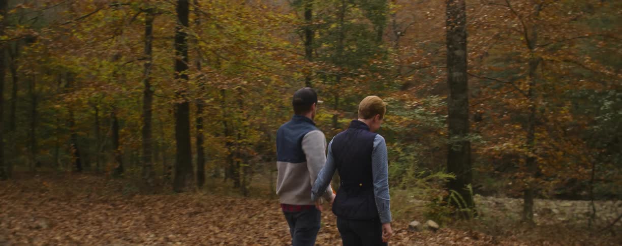 Man and woman hug and walk in the woods with a small dog