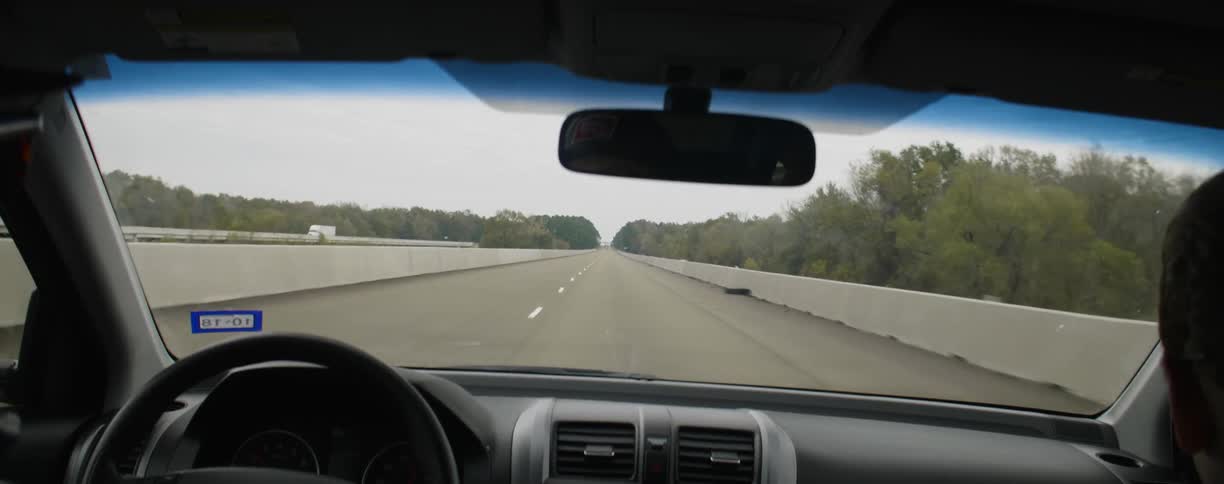 Traveling view looking out a car windshield at a highway