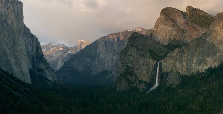 View of tall rocky mountains and a small waterfall splashing off one