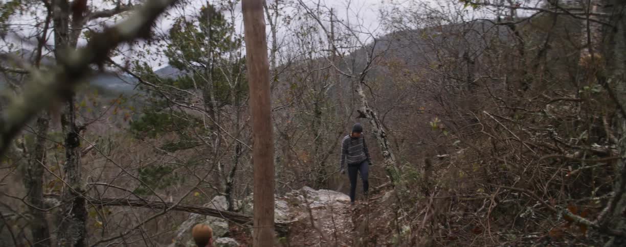 A couple of people on a large rock in the woods