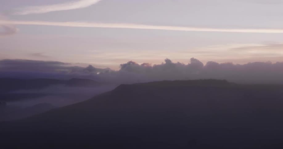 Clouds hang above a foggy mountain top