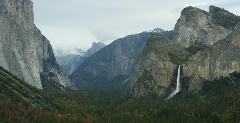 The valley has a forest before a mountain with a waterfall