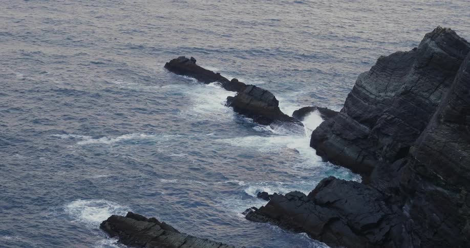 The waves splash against the rocks near the shore