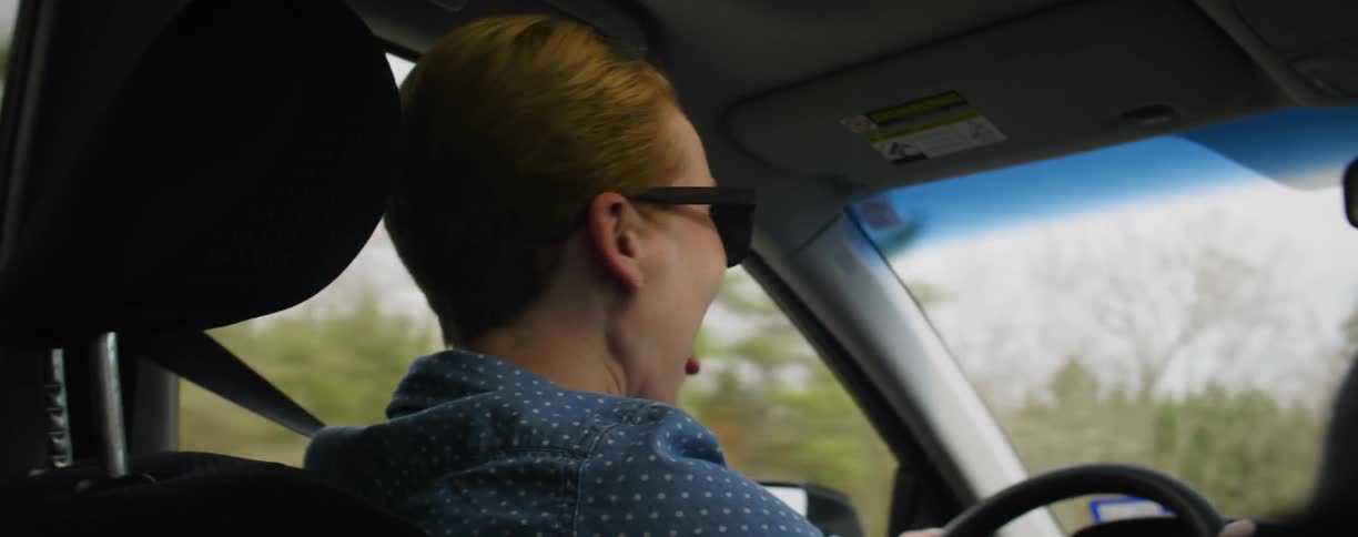 Woman laughing as she drives a car