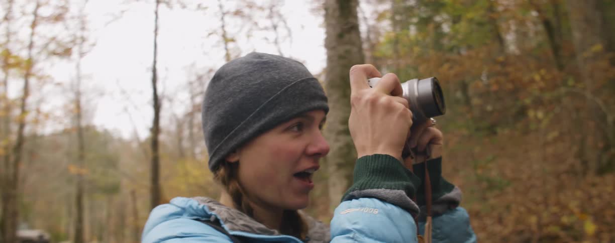 A woman is talking and taking a picture in a forest in autumn