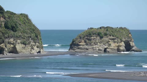 Waves come to shore around a rock island