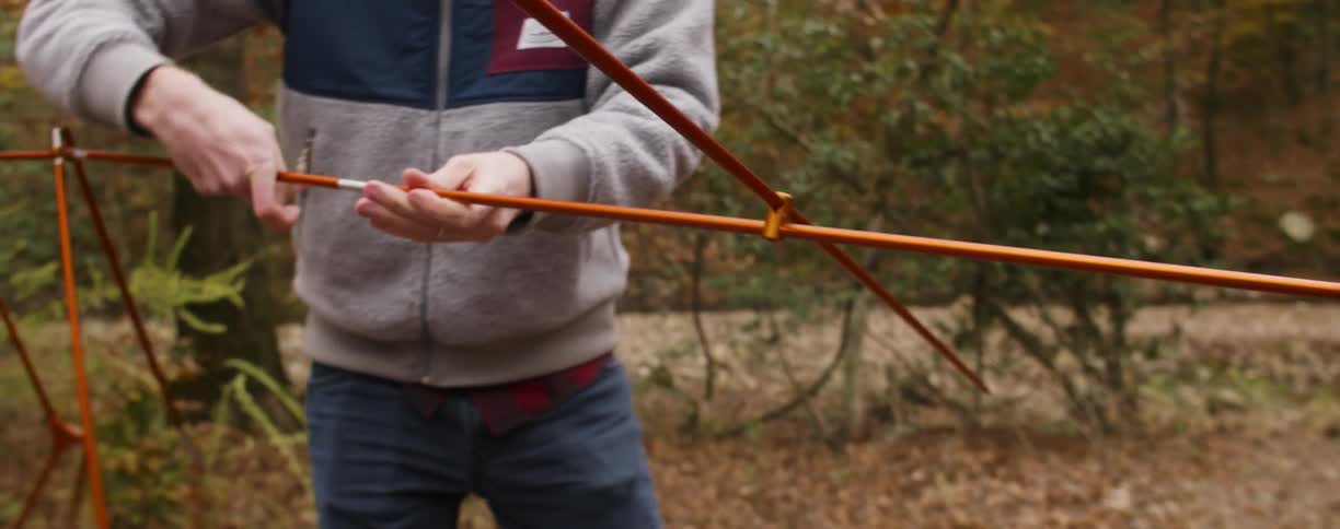 A couple of people holding poles to put a tent together