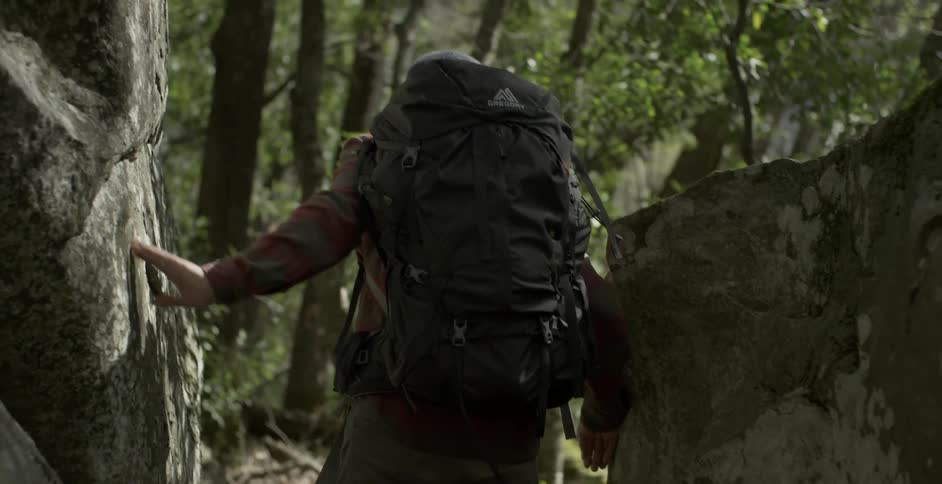 Hiker walking between two large rocks while following a trail