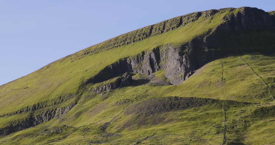 A green covered mountain under a blue sky
