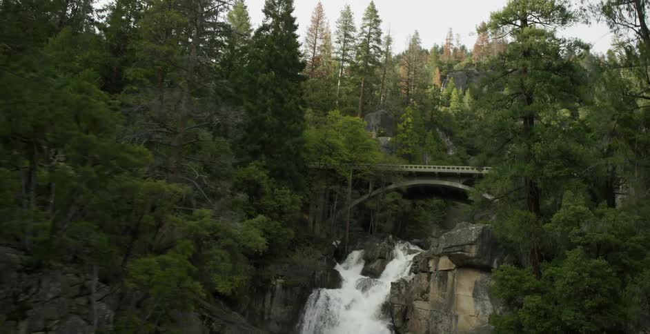 Water splashing down a small waterfall with a bridge over it