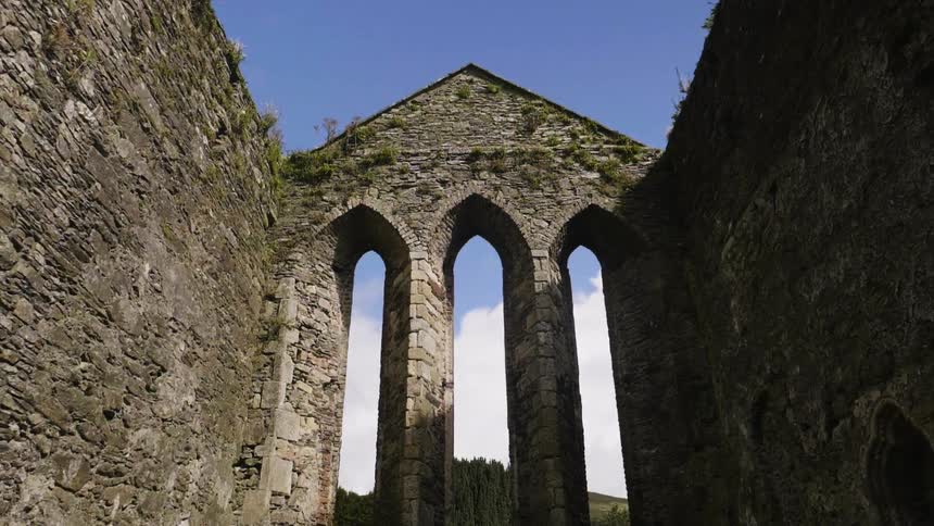 The ruins of a stone building stand out against a cloudy, blue sky