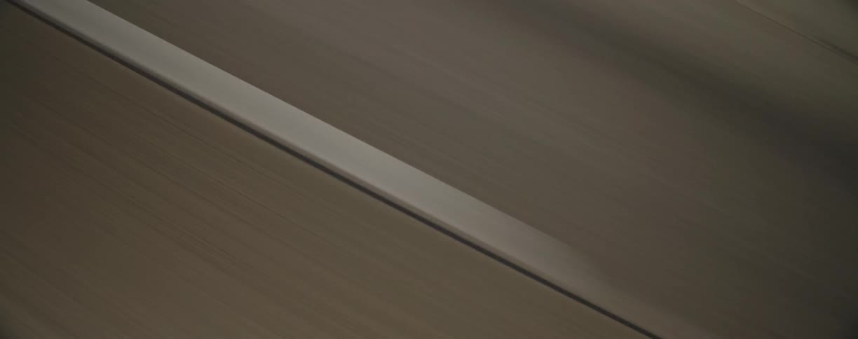 White road markers on the asphalt are passed by at speed