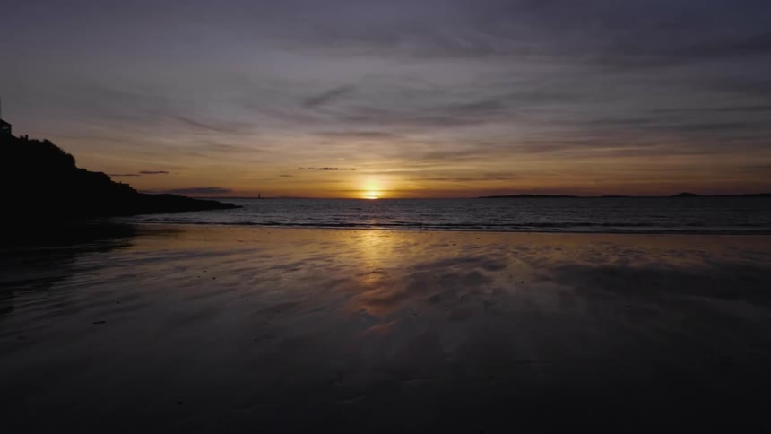 The sun sets into the ocean at a beach