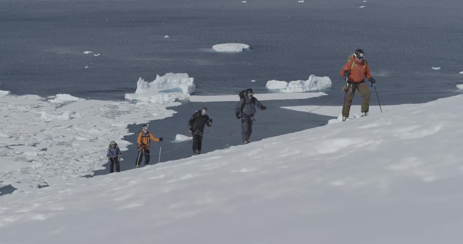 A line of people wearing skis walking up a snowy hill