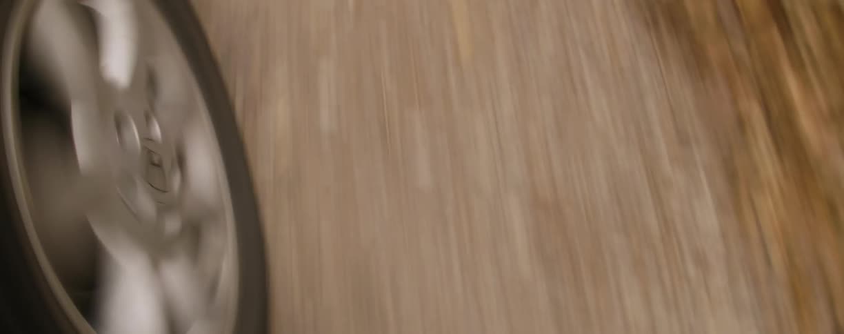 A vehicle's tire rotates as it drives over a dirt road