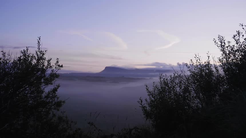 A body of water covered by fog at sunrise