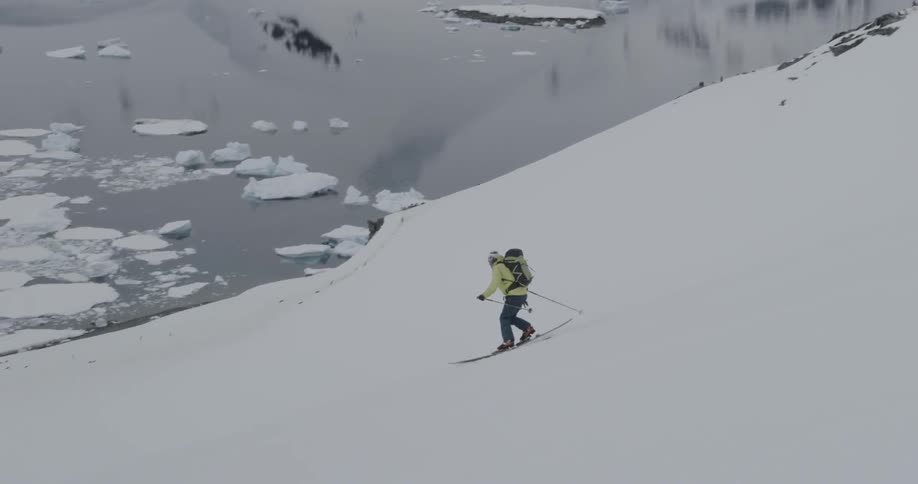 A man is telemark skiing downhill on a steep slope