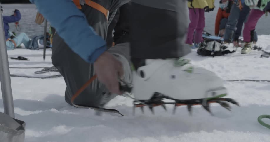 A man attaches crampons to his boots