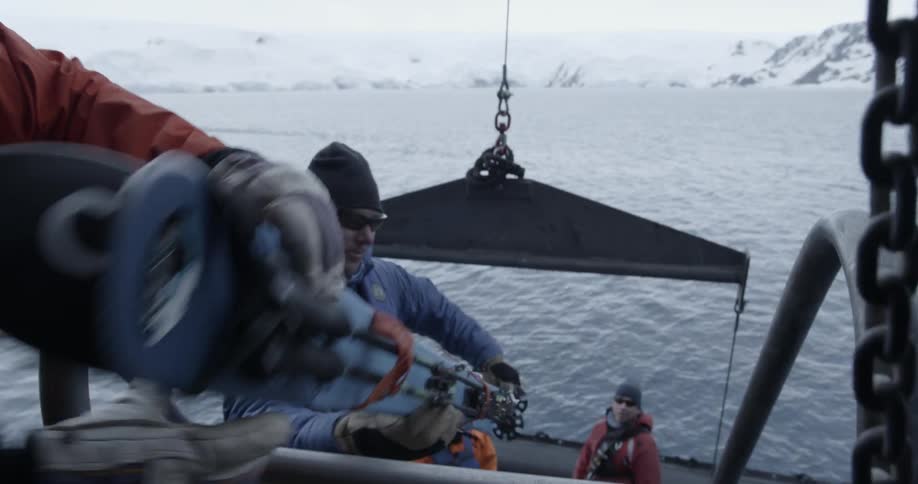 Group of people on a boat pass skis down a small staircase to zodiac
