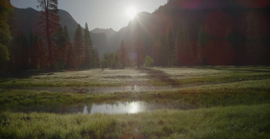 Sun shining over mountains and swampy land