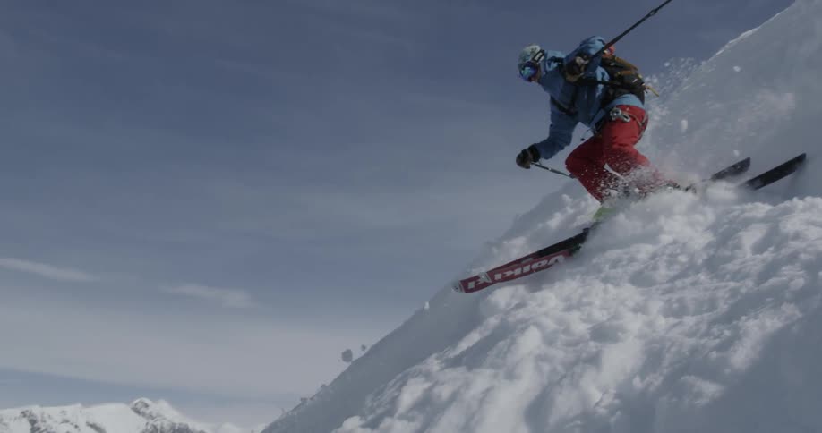 A teenager skiing down a steep slope kicking up the snow