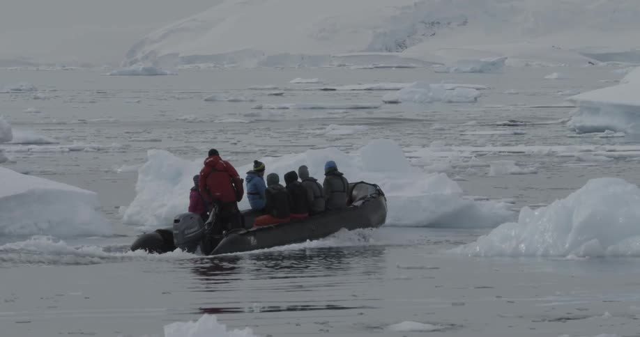 A group of people on a rubber boat going through chunks of ice on the water