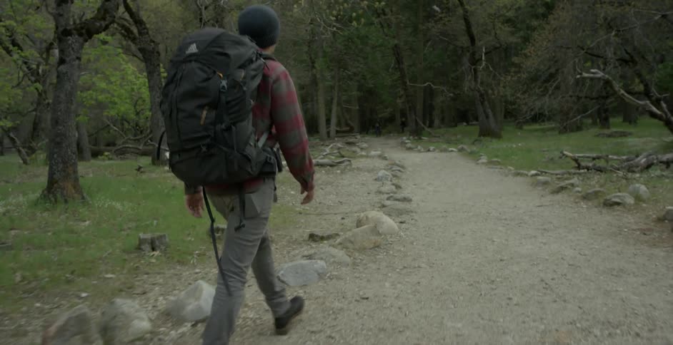 A man backpacking along a trail in the woods