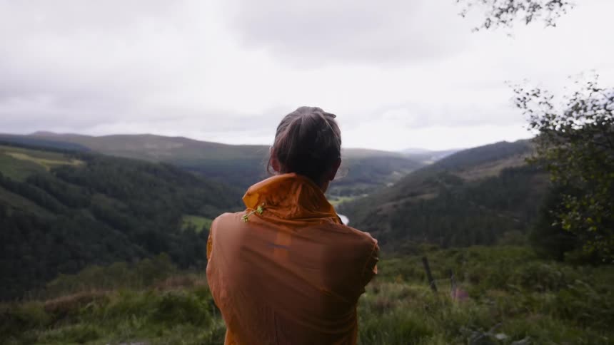 Woman looks out at hilly landscape