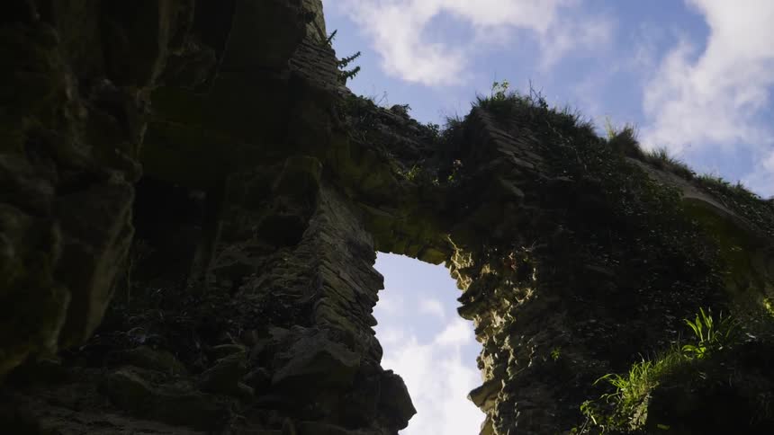 A large rock with a hole in it to walk through covered in moss