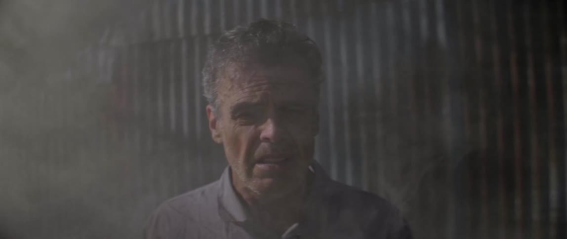 Worried looking elderly man stands outside with smoke curling around him