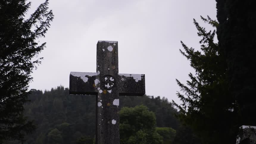 Water drips from a cross shaped gravestone