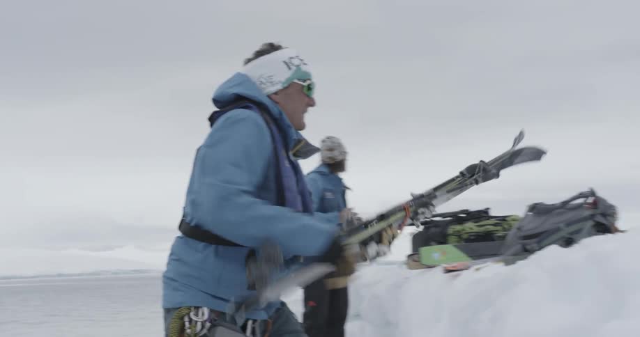 People pass a set of skis along a line of people (tight angle)