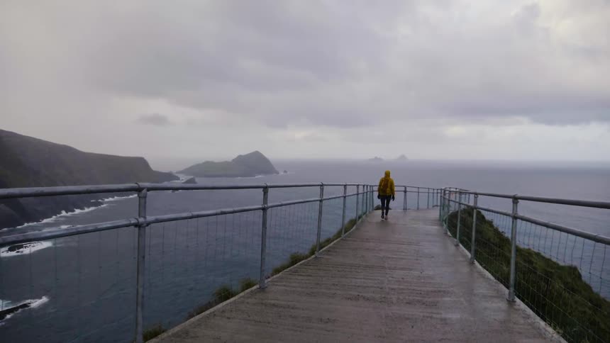 A person walks down a long sidewalk over the ocean