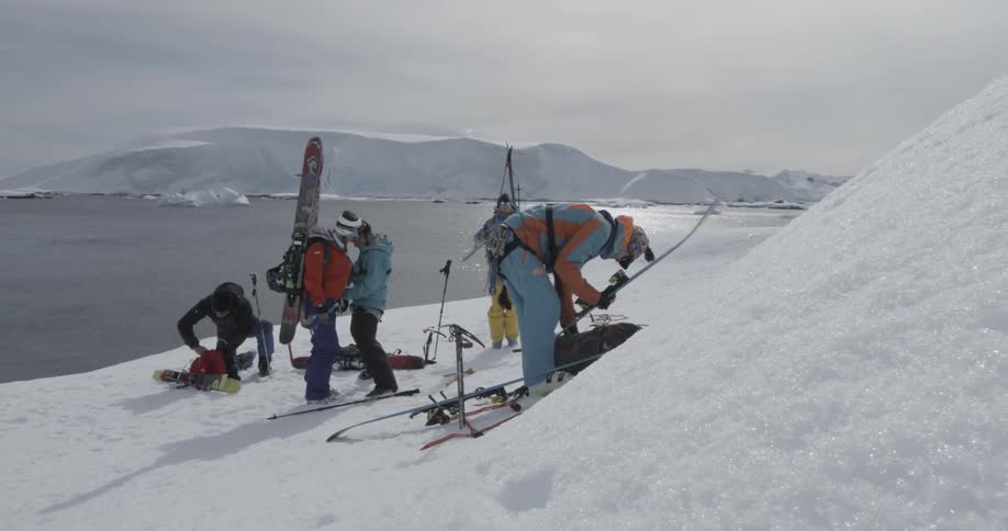 Group of people assembling ski equipment on a snowy shore