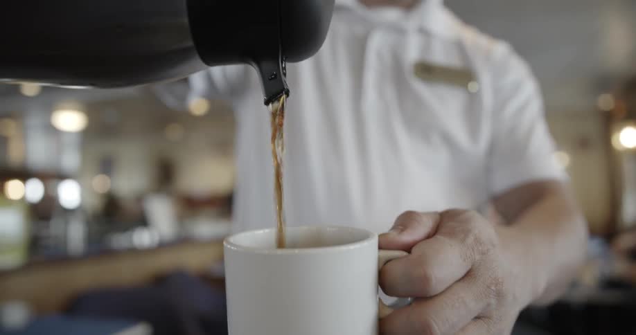 A man pours coffee into a mug