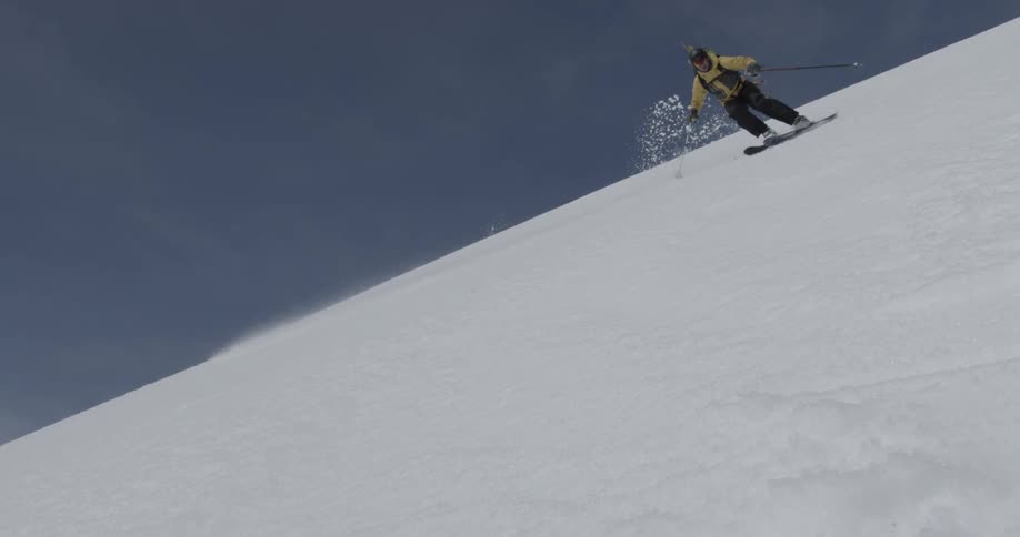 A person skiing fast towards camera on a sunny clear day