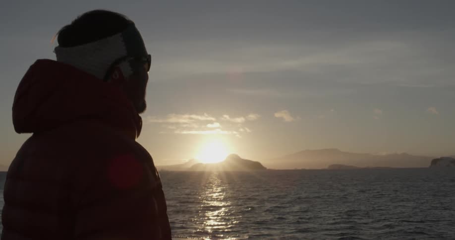 Man looking out at the water at sunset