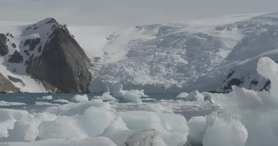 Icebergs and ice float in a sea at the edge of a glacier