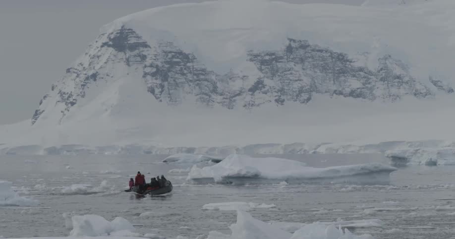 A zodiac boat moving through water covered with ice and snow