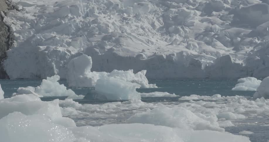 Glacier moving into the ocean filled with sea ice on a sunny day