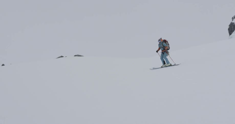 Skiers are going down a slope toward a body of water during the day