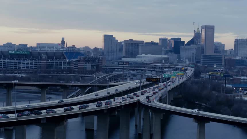 Vehicles driving on a highway over a river next to a city