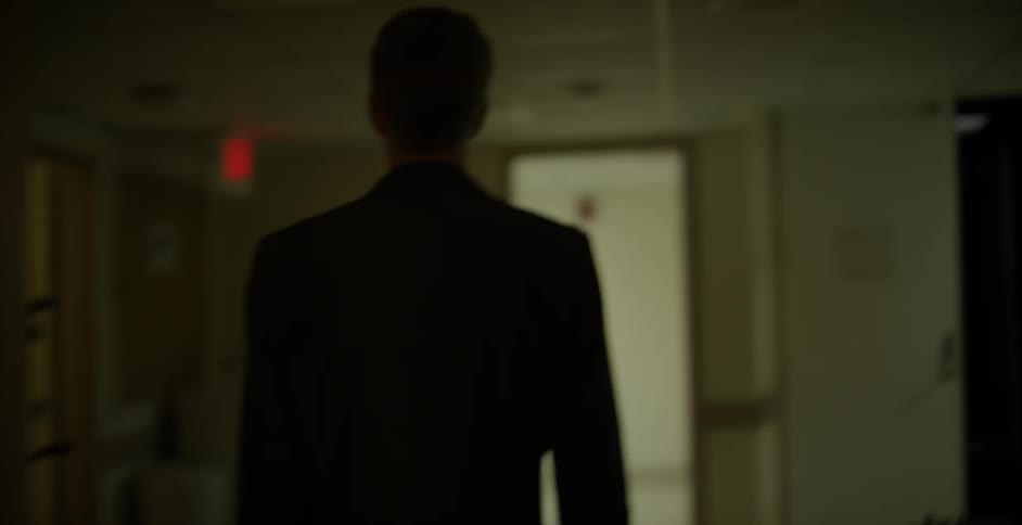 A man is walking through darkened hallways in a building
