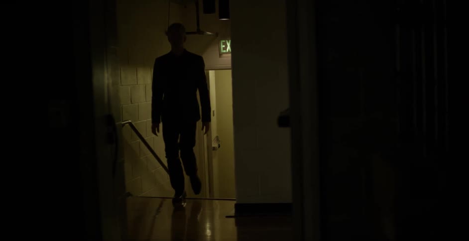 A man walks up stairs in a dark hallway