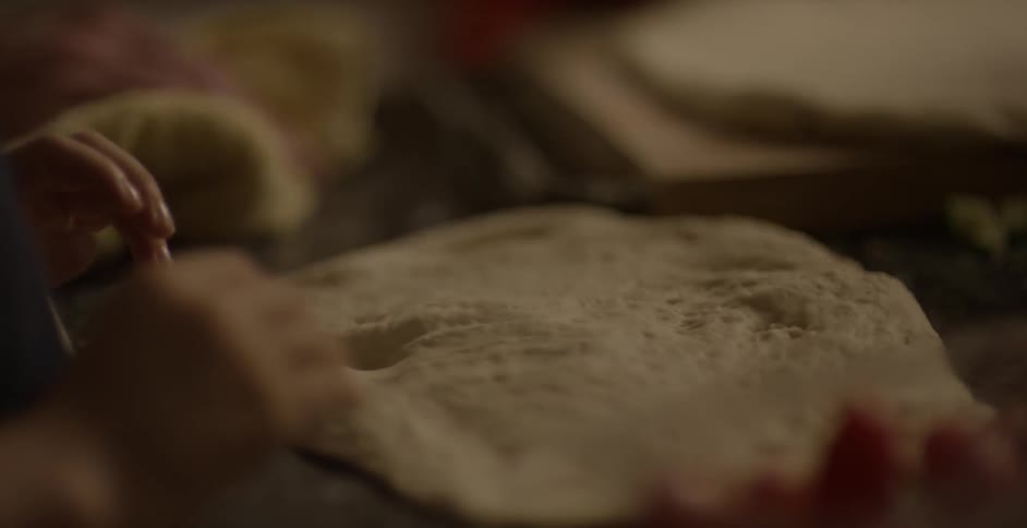 People are flattening dough on a pan
