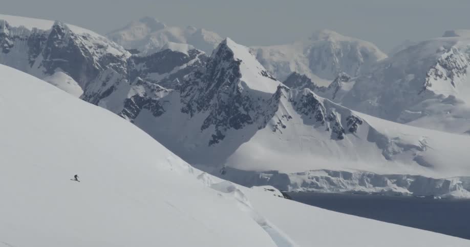 A person is skiing down a very steep glaciated mountain with dramatic backdrop