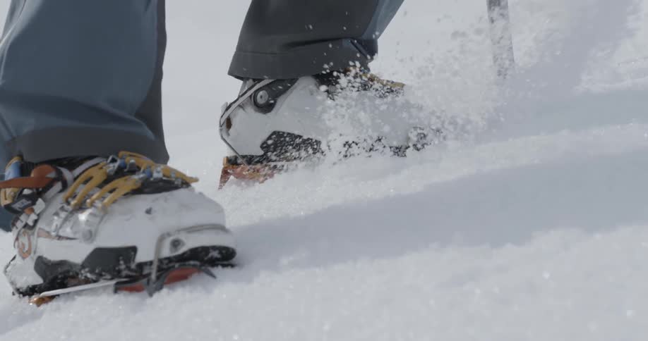 Person wearing crampons climbs up a snowy mountain
