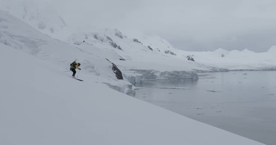 A person skiing down an Antarctic mountain glacier to the ocean below