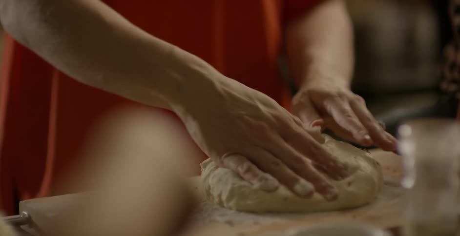 A woman rolls out dough on a floured surface