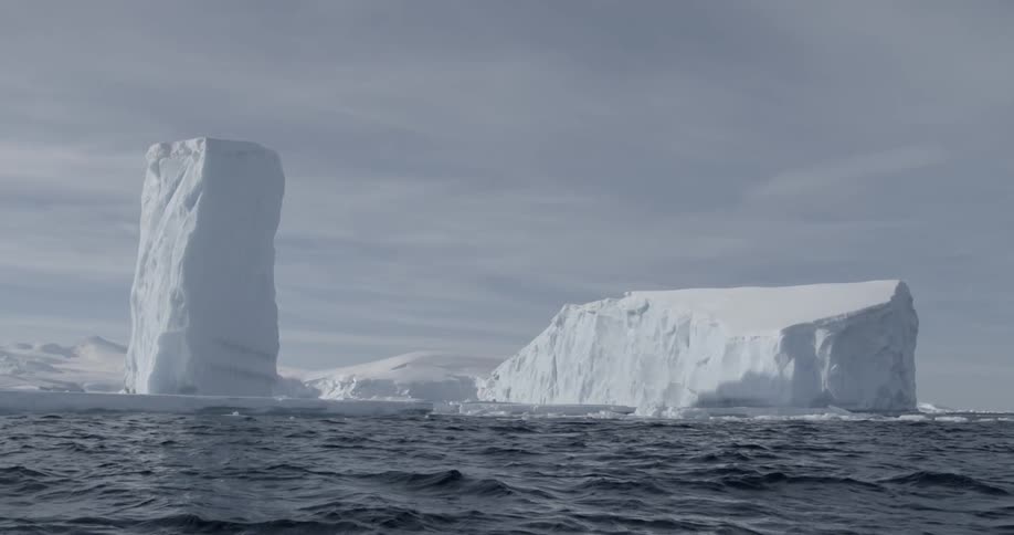 Two massive icebergs floating in a body of water
